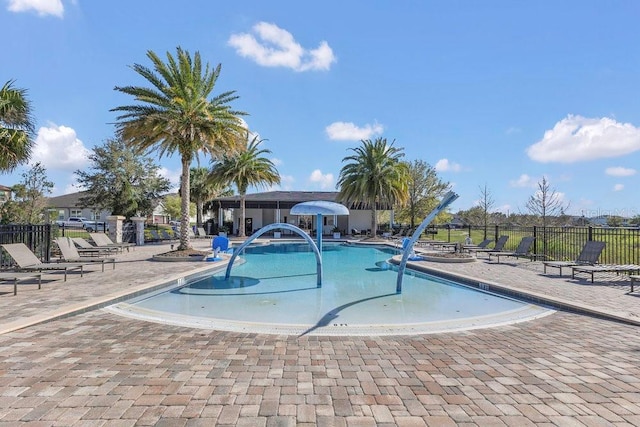 community pool with a patio area and fence