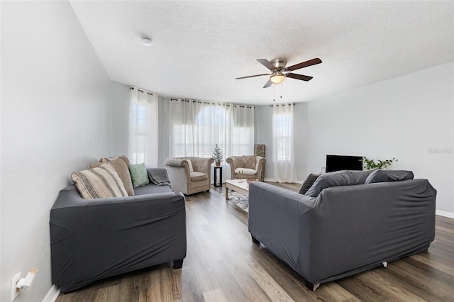 living room featuring a textured ceiling, wood finished floors, a ceiling fan, and baseboards