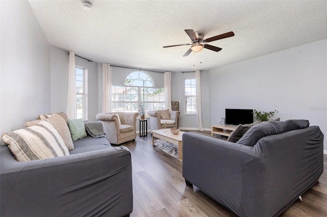 living area with ceiling fan, a textured ceiling, and wood finished floors