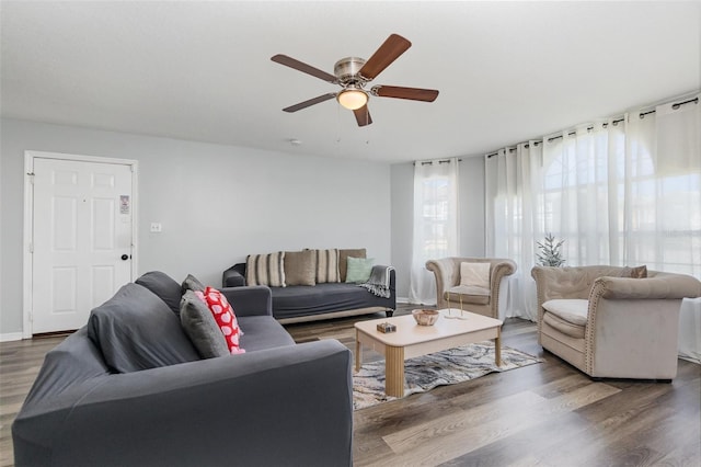 living area with wood finished floors, a ceiling fan, and baseboards