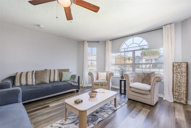 living area featuring a ceiling fan, a textured ceiling, baseboards, and wood finished floors