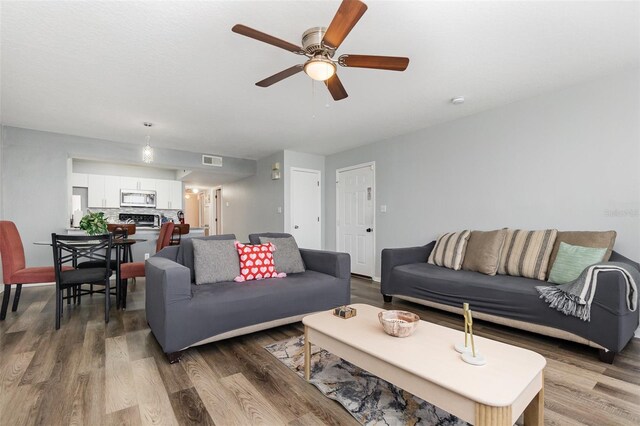 living area featuring wood finished floors, visible vents, and a ceiling fan