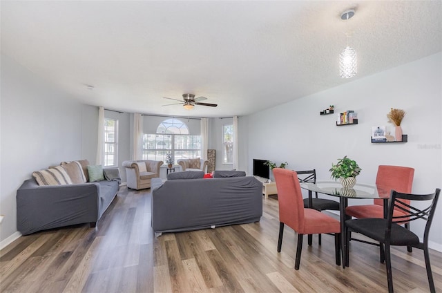 living area featuring light wood-style floors, ceiling fan, and baseboards