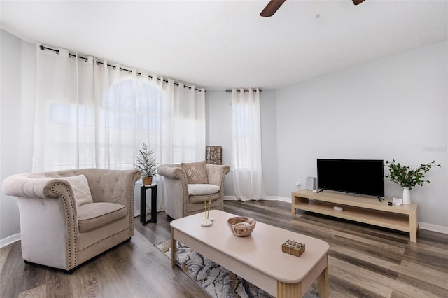 living area with wood finished floors, a ceiling fan, and baseboards