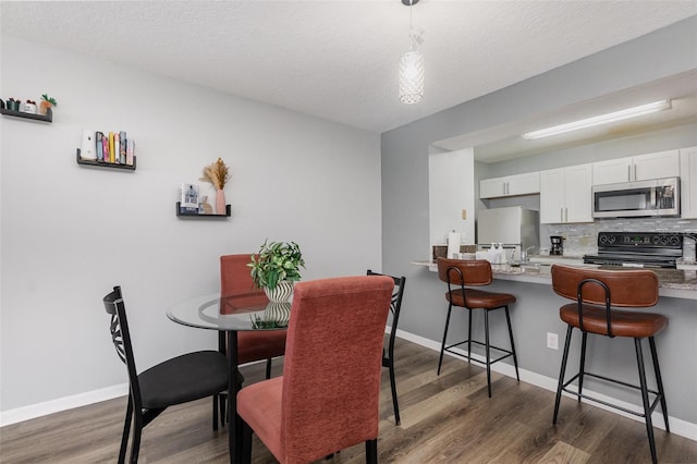 dining area with baseboards and dark wood-type flooring