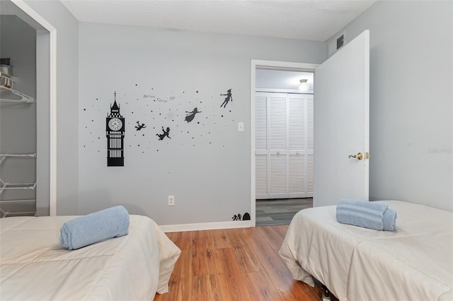 bedroom with a closet, light wood-type flooring, visible vents, and baseboards