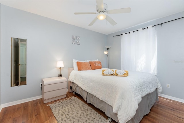 bedroom featuring wood finished floors, a ceiling fan, and baseboards