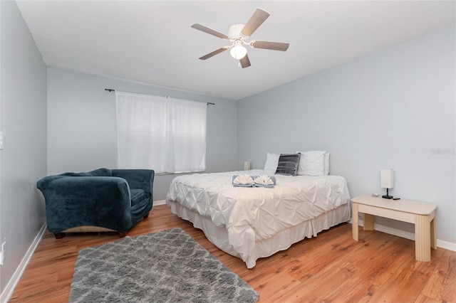 bedroom featuring ceiling fan, light wood-style flooring, and baseboards