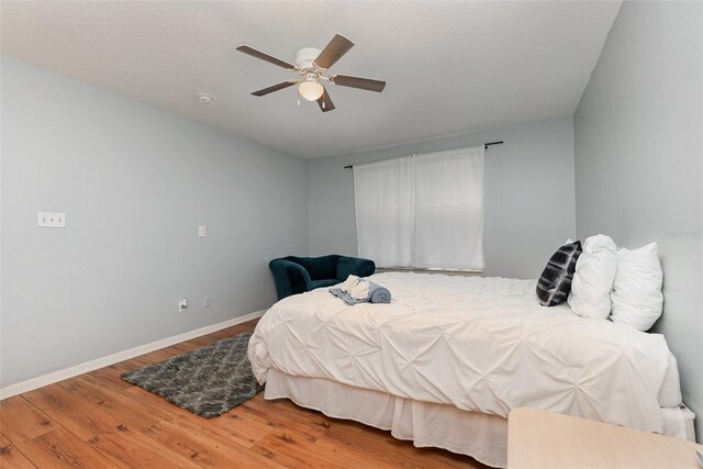 bedroom with ceiling fan, wood finished floors, and baseboards