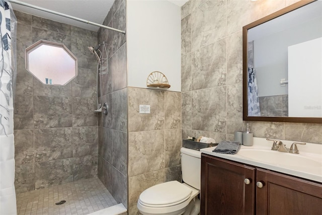 bathroom with toilet, tile walls, tiled shower, and vanity