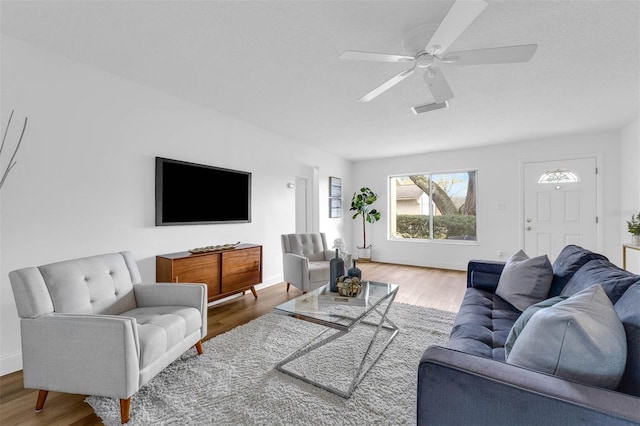 living room featuring a ceiling fan, wood finished floors, visible vents, and baseboards