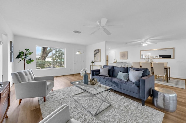 living room featuring visible vents, baseboards, wood finished floors, and a ceiling fan