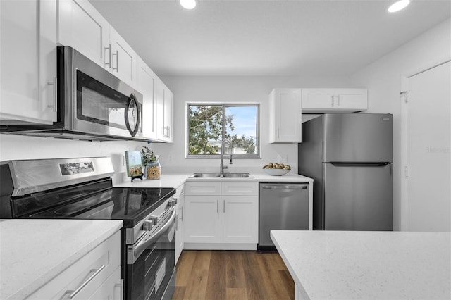 kitchen with dark wood-type flooring, recessed lighting, appliances with stainless steel finishes, white cabinetry, and a sink