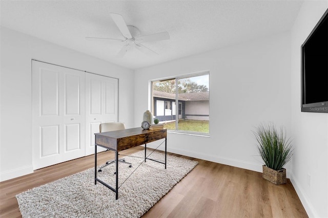 office area featuring ceiling fan, baseboards, a textured ceiling, and wood finished floors