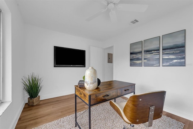 home office featuring baseboards, wood finished floors, visible vents, and ceiling fan