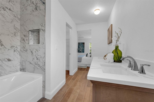 ensuite bathroom with connected bathroom, baseboards, wood tiled floor, a washtub, and vanity