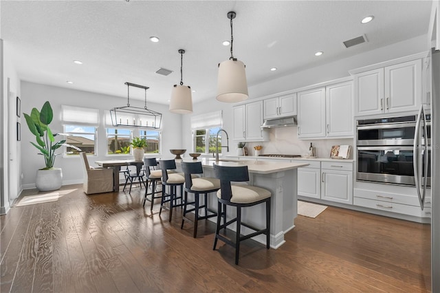 8025 Topsail Pl, Winter Garden, FL 34787 - kitchen with double oven, under cabinet range hood, light countertops, white cabinetry, and a sink