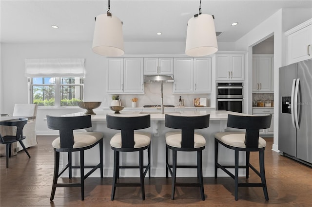 8025 Topsail Pl, Winter Garden, FL 34787 - kitchen featuring appliances with stainless steel finishes, under cabinet range hood, light countertops, backsplash, and white cabinets