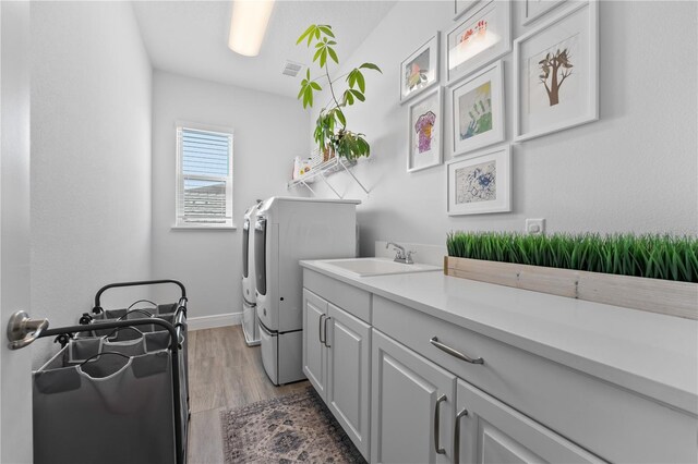 8025 Topsail Pl, Winter Garden, FL 34787 - laundry room featuring washing machine and dryer, cabinet space, light wood-style flooring, and baseboards