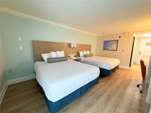 bedroom with ornamental molding, baseboards, and wood finished floors