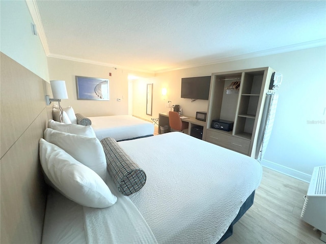 bedroom with baseboards, a textured ceiling, wood finished floors, and ornamental molding