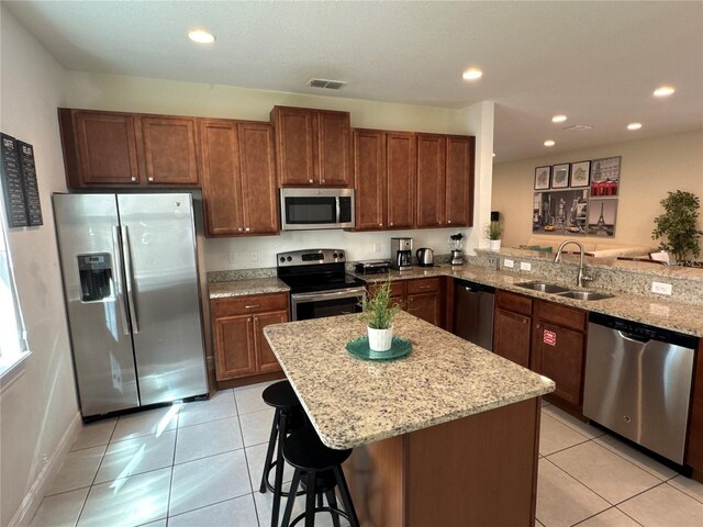 kitchen featuring light tile patterned floors, recessed lighting, a sink, appliances with stainless steel finishes, and light stone countertops