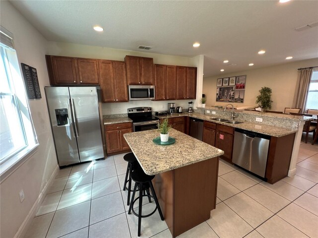 kitchen with a breakfast bar, stainless steel appliances, visible vents, a sink, and a peninsula