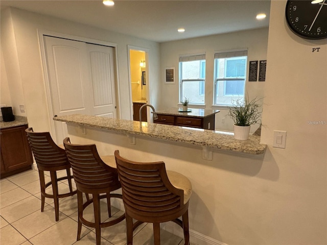 bar with recessed lighting, a sink, baseboards, and light tile patterned floors