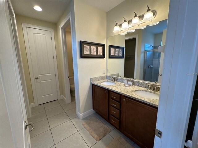 bathroom featuring a sink, a shower stall, toilet, and tile patterned floors