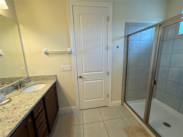 full bath featuring a stall shower, tile patterned flooring, vanity, and baseboards