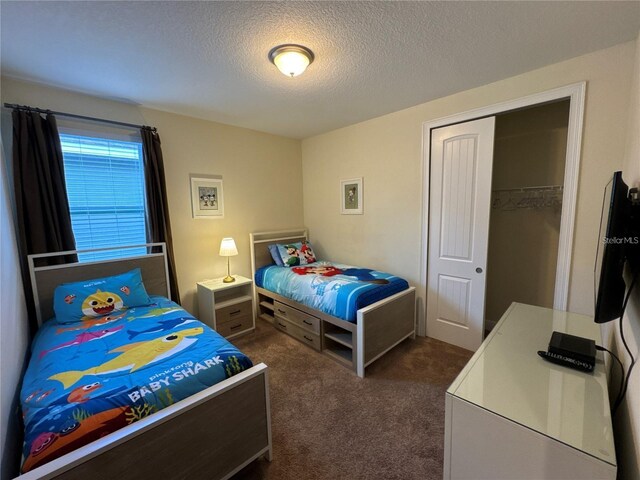 bedroom with a closet, dark colored carpet, and a textured ceiling