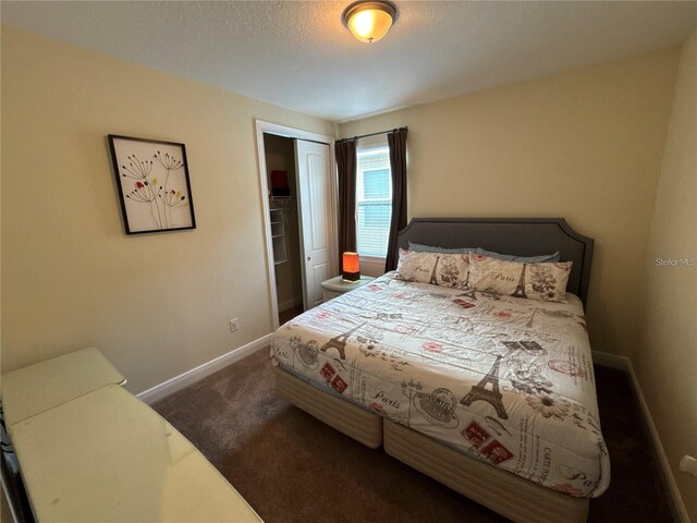 bedroom with dark colored carpet, a closet, a textured ceiling, and baseboards
