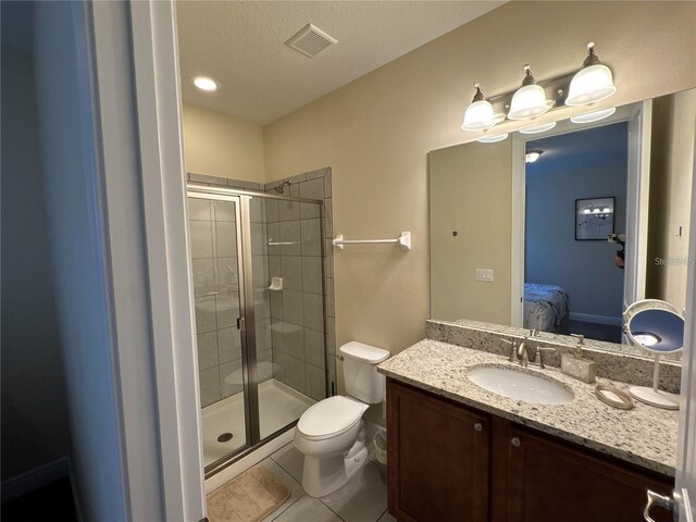 ensuite bathroom with connected bathroom, toilet, vanity, a shower stall, and tile patterned floors