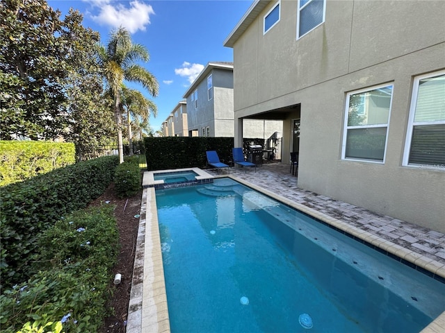view of pool featuring a patio, a fenced backyard, and a pool with connected hot tub