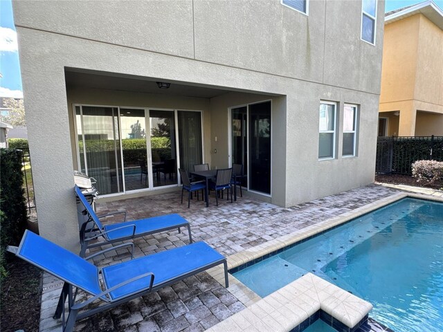 rear view of property featuring a fenced in pool, a patio area, fence, and stucco siding