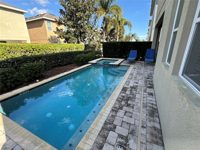 view of pool featuring a patio area, a fenced backyard, and a pool with connected hot tub