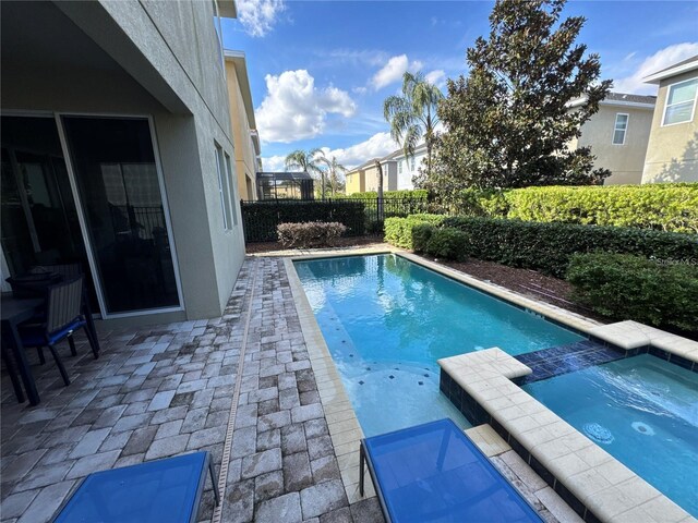 view of pool featuring a patio area, a pool with connected hot tub, and fence