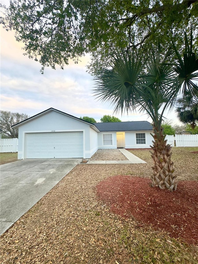 view of front of home featuring concrete driveway, fence, a garage, and stucco siding