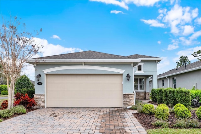 view of front of home with stone siding, stucco siding, decorative driveway, and a garage