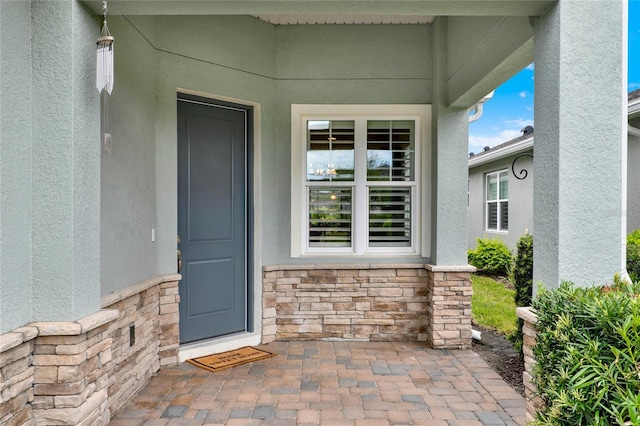 property entrance featuring stone siding and stucco siding