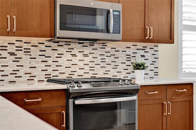 kitchen featuring decorative backsplash, appliances with stainless steel finishes, brown cabinetry, and light countertops