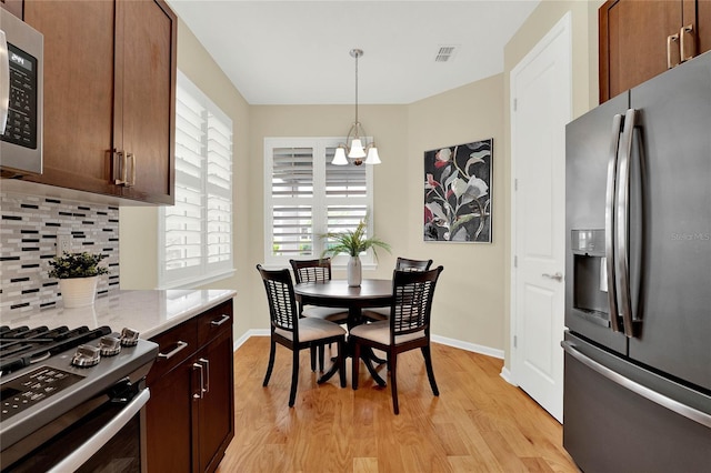 dining room featuring a notable chandelier, baseboards, visible vents, and light wood-type flooring