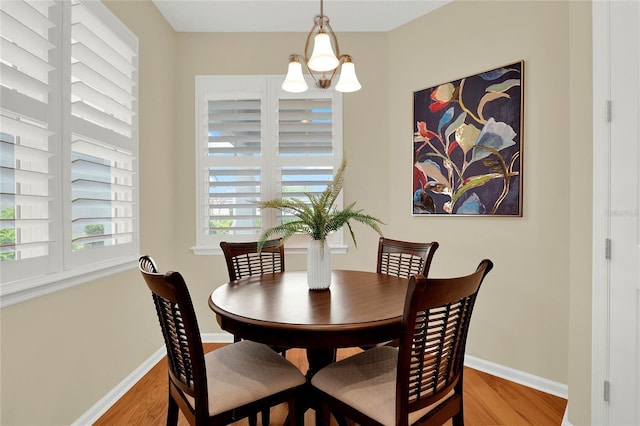 dining room featuring a chandelier, baseboards, and wood finished floors