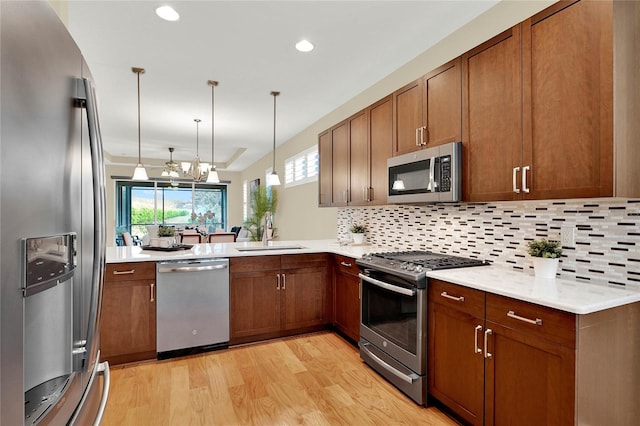 kitchen with backsplash, light countertops, light wood-style flooring, stainless steel appliances, and a sink