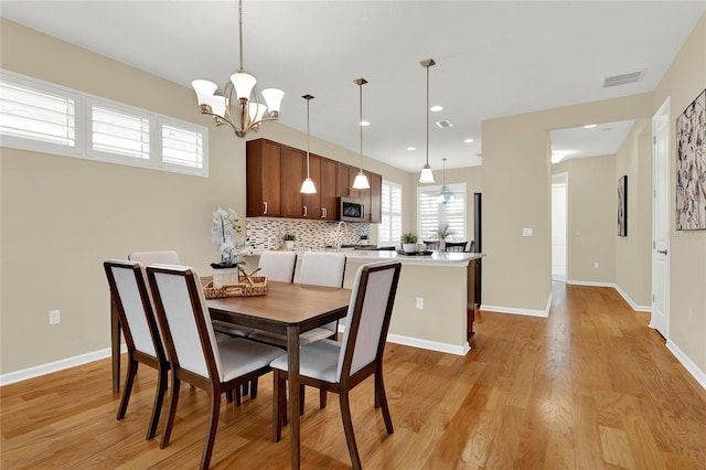 dining area with a chandelier, visible vents, light wood-type flooring, and baseboards