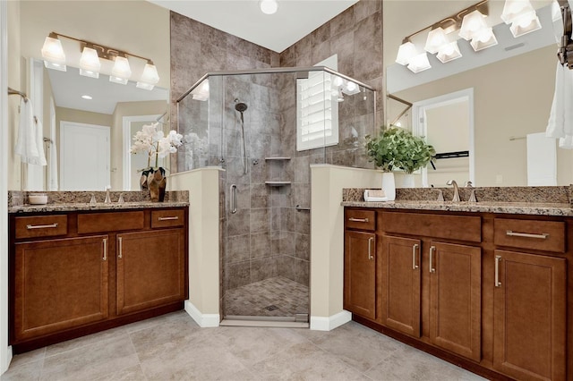 bathroom featuring a sink, a shower stall, and two vanities