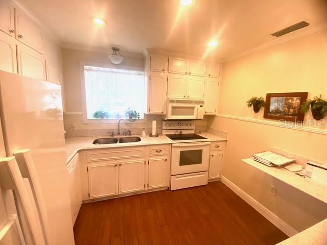 kitchen with visible vents, light countertops, dark wood-style floors, white appliances, and a sink