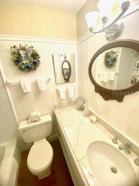 bathroom featuring vanity, an inviting chandelier, toilet, and a bathtub