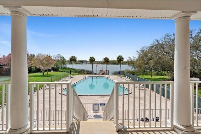 pool featuring a patio area, a lawn, and a water view