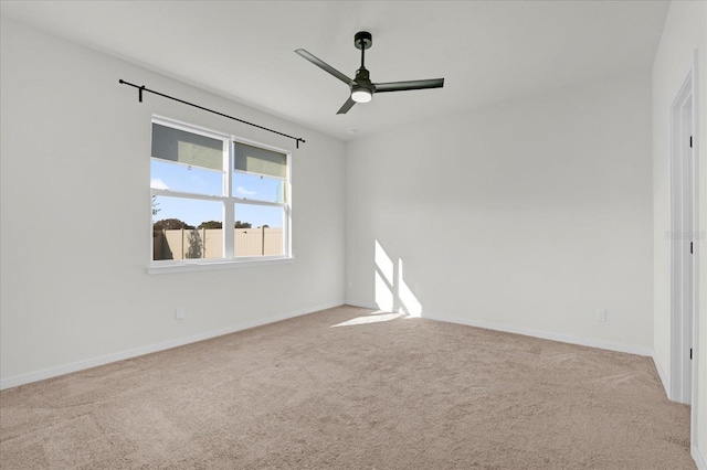 carpeted spare room featuring ceiling fan and baseboards